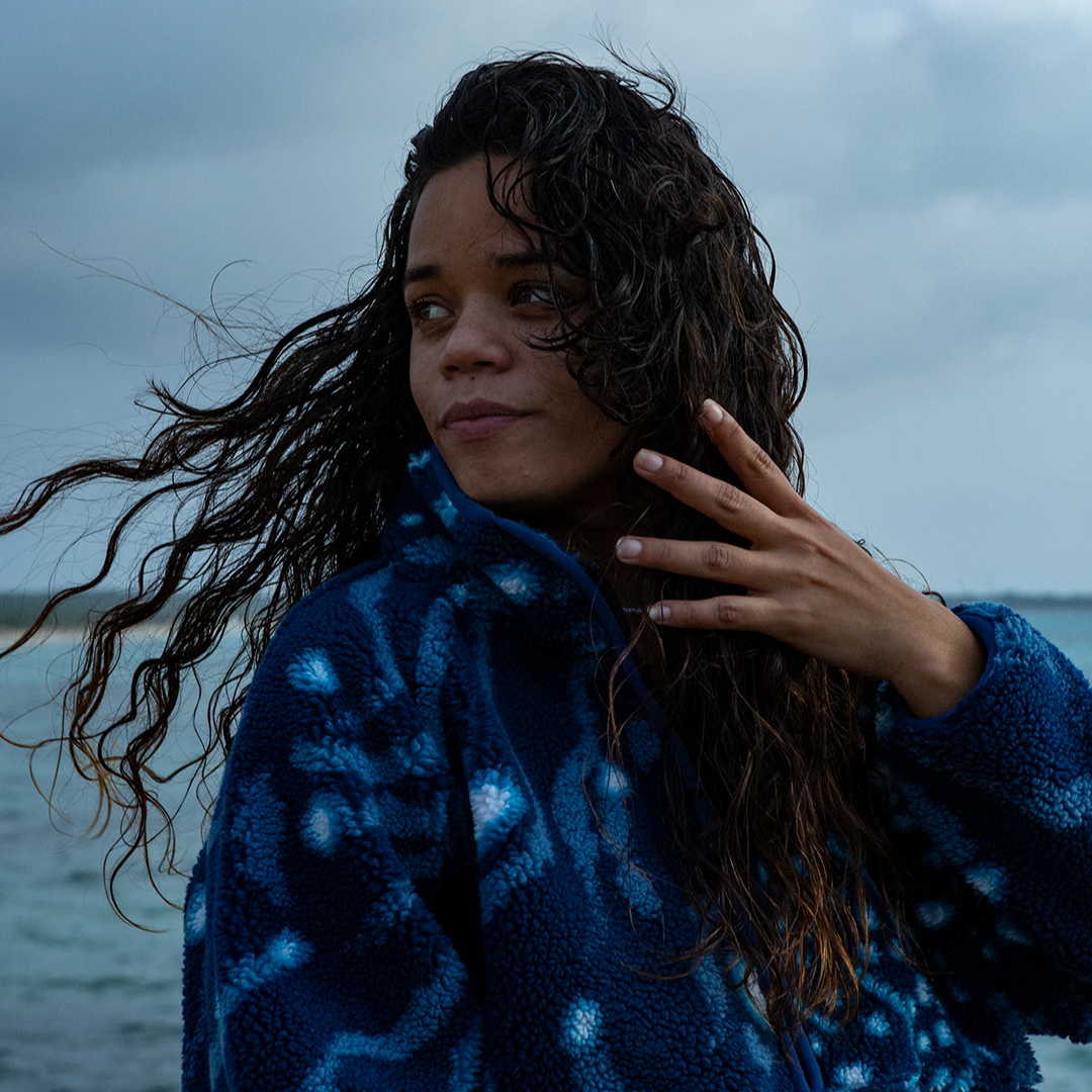 Model standing on the coast in the WHALE SHARK print fleece from NAUTRA, with the wind blowing through her hair.